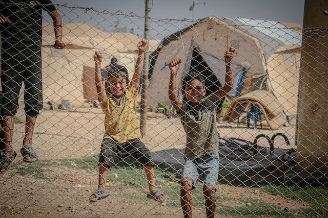 barn bakom stängsel i flyktingläger